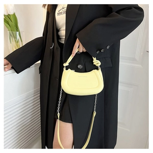 Detalle del bolso hobo amarillo claro con asa anudada y correa de cadena de plata