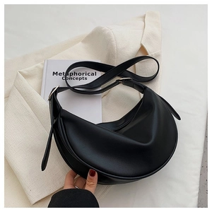 Detail of black crescent shoulder bag with adjustable strap on textured background