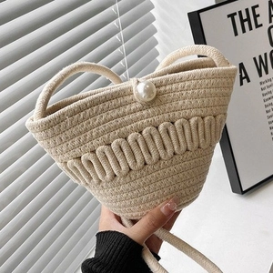 Handmade cream woven straw bucket bag with pearl buckle closure and wavy knit texture