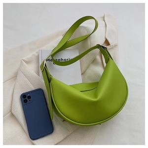 Detail of lime green crescent shoulder bag with golden hardware on a minimal background