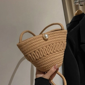 Detailed view of handmade woven straw bucket bag featuring a large pearl clasp closure