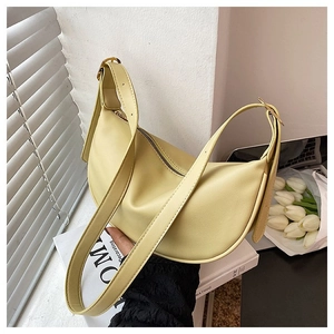 Detail of creamy yellow crescent shoulder bag with golden zipper and adjustable strap