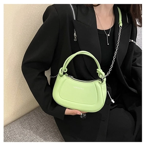 Detalle del bolso de cuero verde neón con cadena plateada y logotipo de moda impreso