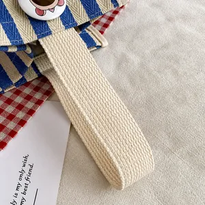 Detailed close-up of striped canvas handbag handle with premium cotton webbing texture
