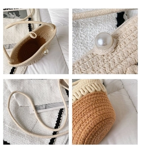 Detail of straw bucket bag featuring two-tone weaving and a large pearl ornament decoration