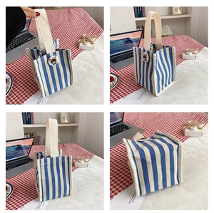 Detail view of blue and white striped canvas tote with cartoon badge on a checkered table