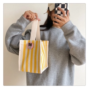 Detail of yellow and white striped canvas tote bag with a cute pink cartoon brooch