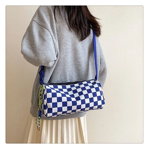 Rear view of a model wearing a blue and white checkered cylindrical crossbody canvas bag