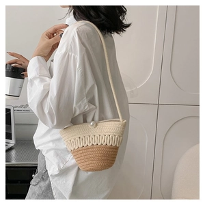 Detail of straw bucket bag with large pearl clasp and wavy woven texture on the strap