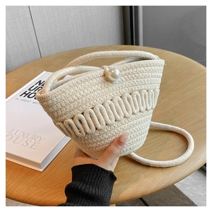 Detail of handmade woven straw bucket bag with elegant pearl closure and cotton rope texture