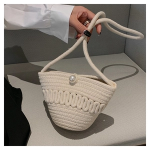 Detail of hand-woven cream cotton rope bucket bag featuring an elegant pearl clasp