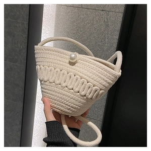 Detail of woven straw bucket bag with oversized pearl accent and thick rope shoulder strap