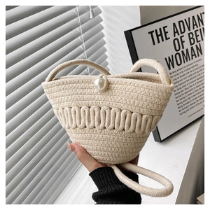 Detail of hand-woven cream bucket bag with unique knot texture and pearl closure button