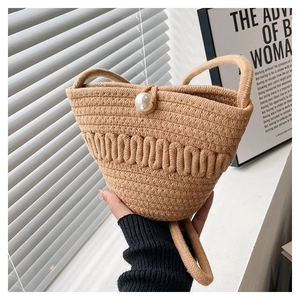 Detail of woven straw bucket bag with elegant pearl clasp and rope handle texture