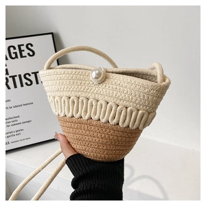Detail of straw bucket bag with cotton rope weave and a large pearl button closure