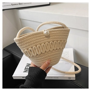 Detail of cream woven bucket bag with rope texture and elegant large pearl clasp