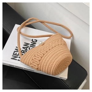 Detailed view of mini woven bucket bag featuring a large pearl clasp and rope strap