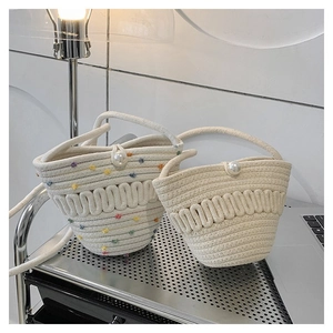 Detail of woven straw bucket bag with pearl closure and wavy textured cotton rope craftsmanship