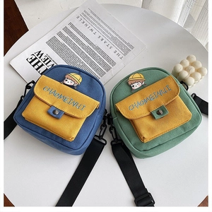Detalle de bolsos bandolera de lona con personaje de dibujos animados y bordados