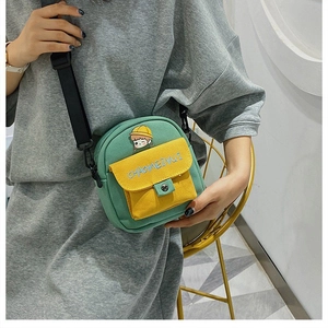 Detalle de bandolera de lona verde y amarilla con parche de niña adorable y bordado