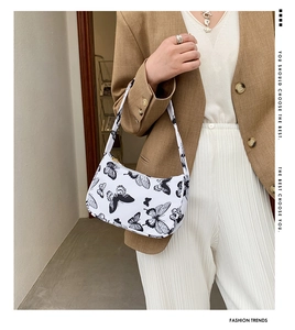 Detail of printed butterfly pattern on white shoulder bag styled on a model's shoulder