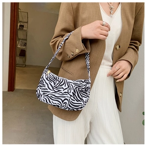 Detail of zebra print baguette bag showing its textured surface and gold metal zipper