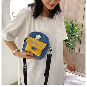 Detalle del bolso bandolera de lona en azul y amarillo con bordado y correa ajustable