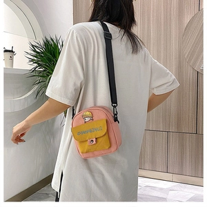 Bolso bandolera de lona rosa con solapa amarilla y parche de dibujo animado en una modelo