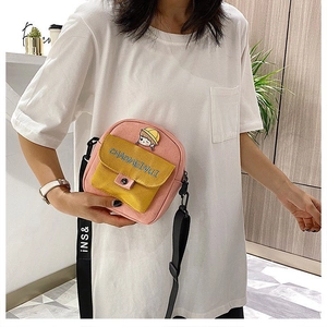 Detalle del bolso bandolera de lona rosa y amarillo con parche de niña y bordado