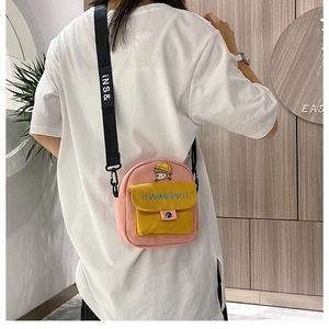 Detalle de bolso bandolera de lona rosa con bordado y correa ancha de nailon