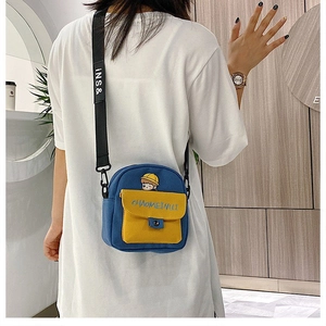 Detalle del bolso bandolera de lona azul y amarillo con bordado de dibujos y correa