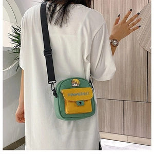 Detalle del bolso bandolera de lona en contraste verde y amarillo en una modelo mujer