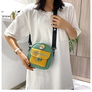 Detalle del bolso bandolera de lona verde con parche de dibujos y correa ajustable