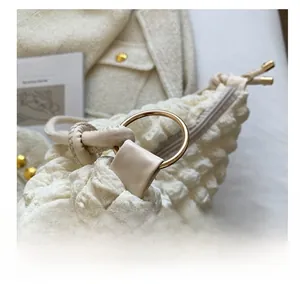 Détail de la boucle métallique dorée et de la texture matelassée blanc cassé du sac