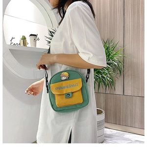 Detalle del mini bolso bandolera de lona verde y amarilla con insignia y correa