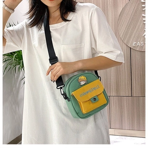 Detalle del bolso bandolera de lona verde y amarilla con bordado de dibujos animados