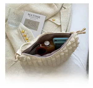 Vue intérieure du sac matelassé crème montrant la capacité avec lunettes et mobile