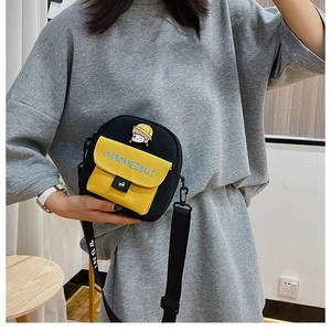 Detalle del estampado de niña y bolsillo amarillo en el bolso bandolera de lona negra