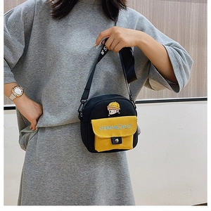Detalle de bolso bandolera de lona con bordado de dibujos y bolsillo amarillo contraste