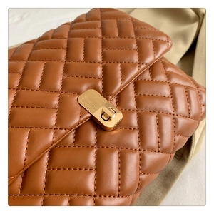 Detail of dark brown quilted shoulder bag featuring elegant golden metal twist lock closure