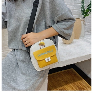 Detalle del bolso bandolera de lona blanca con bolsillo amarillo y bordado de dibujo