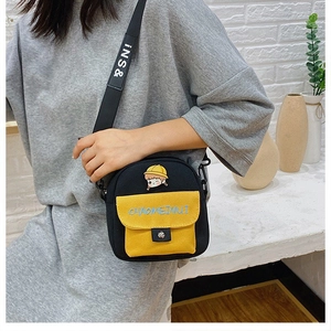 Detalle del bolso bandolera de lona con parche de niña animada y bordado en bolsillo amarillo