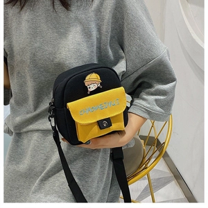 Vista detallada del bolso bandolera de lona con bolsillo amarillo y bordado animado