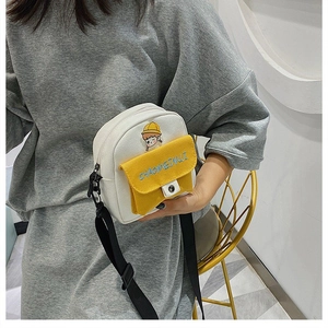 Detalle de mini bolso bandolera de lona blanca con parche de dibujo y bolsillo amarillo