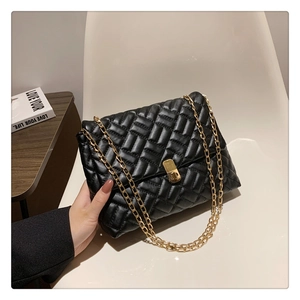 Detail of black woven leather shoulder bag with gold chain strap and metal twist lock