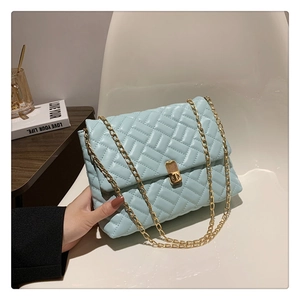 Detail of mint green quilted bag with woven texture and golden metal rotary lock
