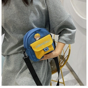 Detalle de bolso bandolera de lona azul y amarillo con bordado de dibujos animados