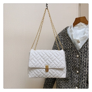 Detail of white quilted handbag with golden square twist lock and double chain straps