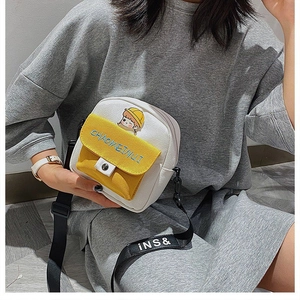 Detalle del bolso bandolera de lona con parche de dibujos y contraste amarillo-blanco