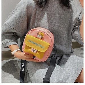 Detalle del bolso bandolera de lona rosa con bolsillo amarillo y gráfico de dibujos